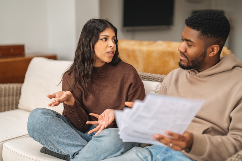 Couple in a heated discussion over financial documents at a table.