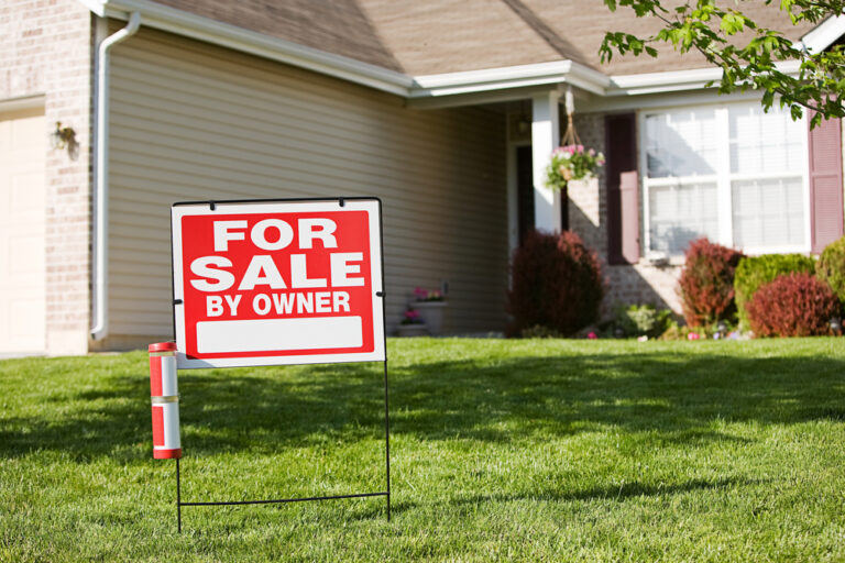 For sale by owner sign in front of a house.