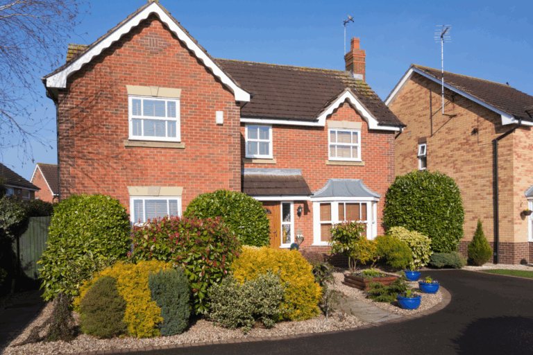 A tidy red-brick detached house with landscaped front garden and driveway, demonstrating strong curb appeal for property sales