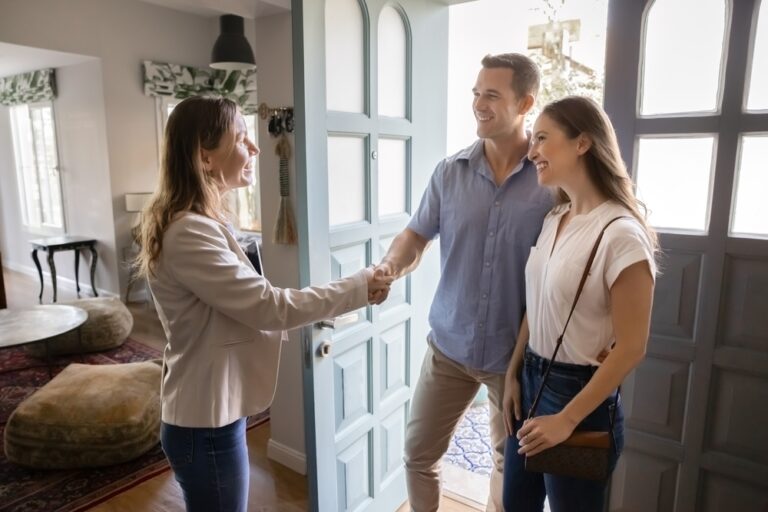 A couple shaking hands in front of a door.