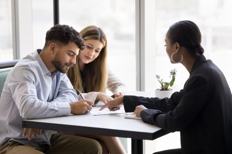 Three people collaborating at a table with a pen and paper.