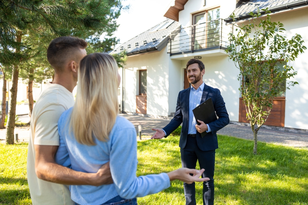 A man and woman consult with a real estate agent in an office setting.