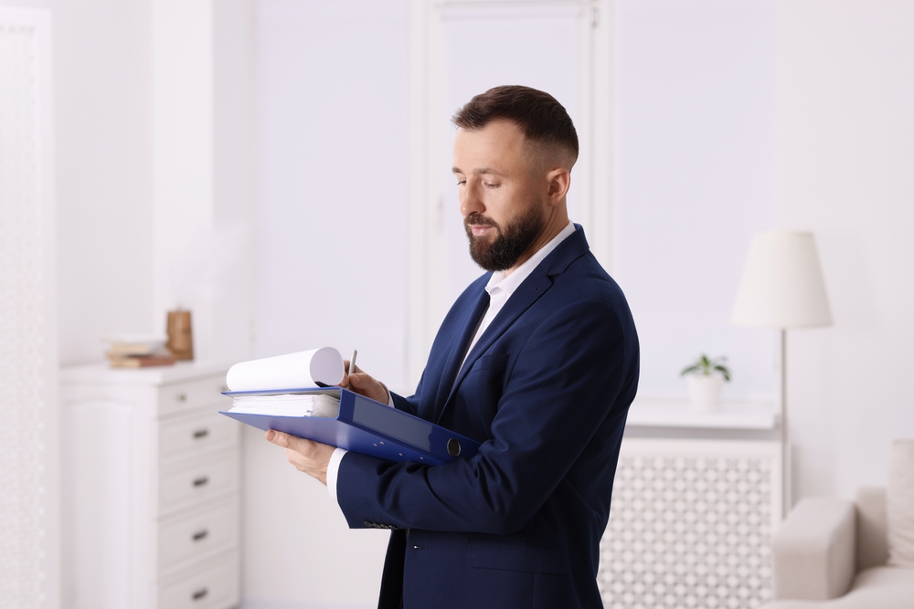A man in a suit reviews a folder, assessing a property valuation.