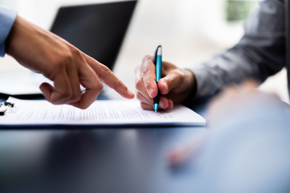 Two people signing a document together at a table.