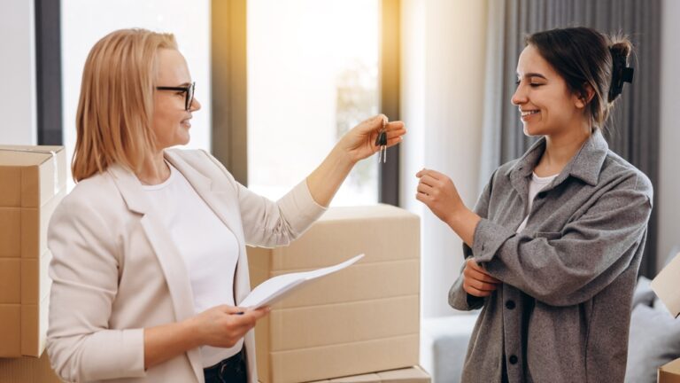 Woman estate agent hands over keys to a new homeowner in an apartment.