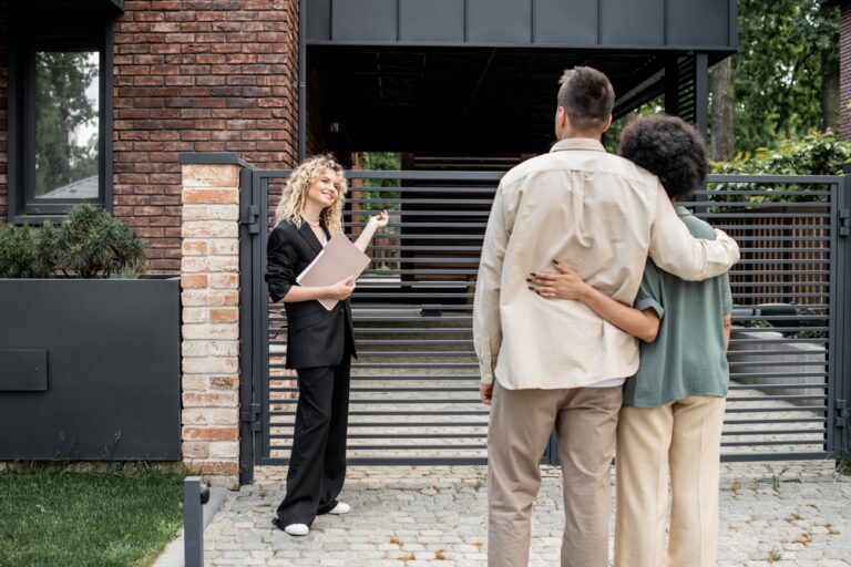 A man and woman stand with an estate agent in front of a house.
