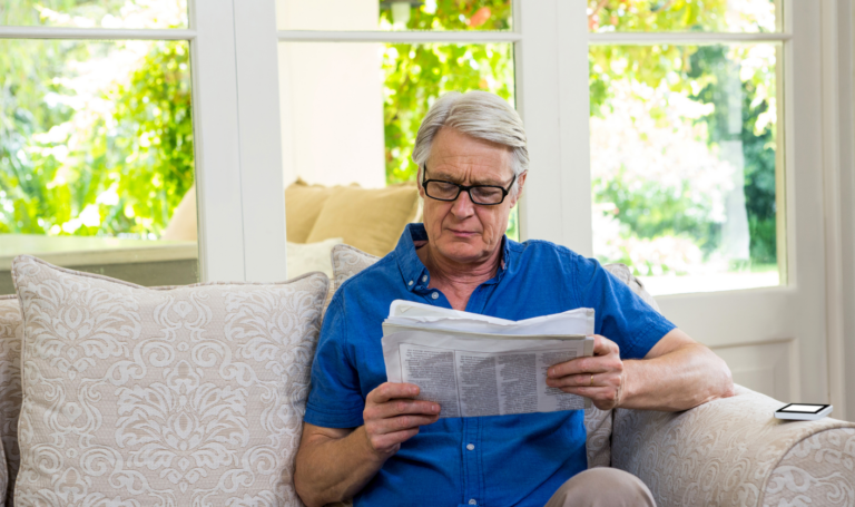 Landlord sitting on a sofa reading documents while considering selling a rented property or moving back into it