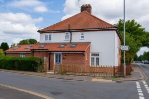 A white house with a red roof against a clear blue sky.