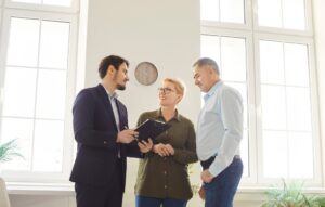 Estate agent discussing property options with two clients in an office.