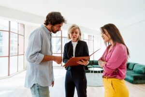 Three people in an open living room during an estate showing.