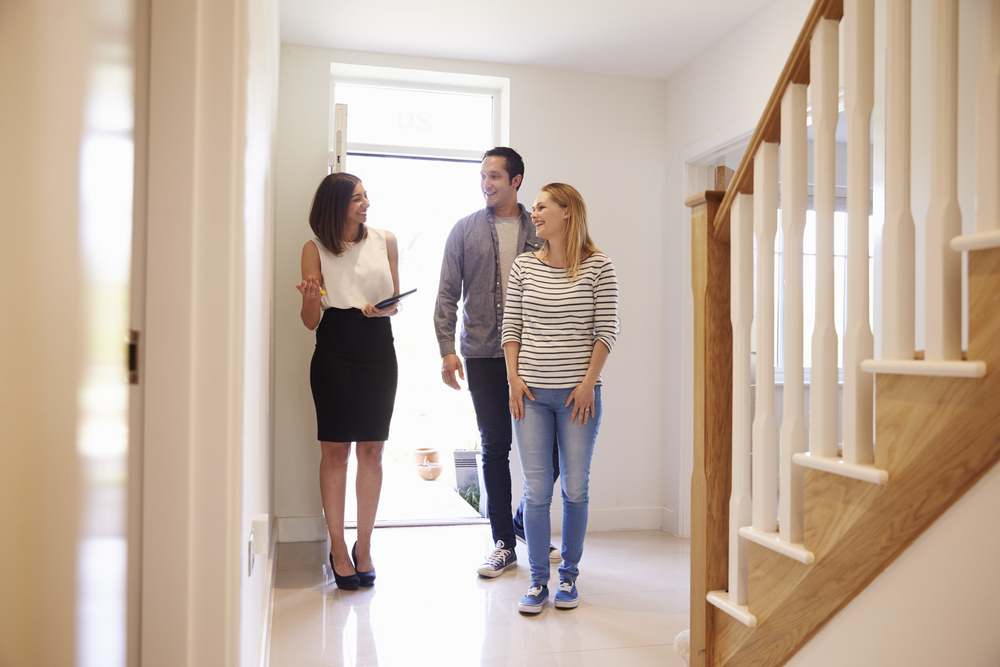A man and woman in a hallway, with an estate agent showing a property tour
