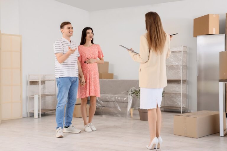 A man and woman stand in a room filled with boxes, discussing the property.