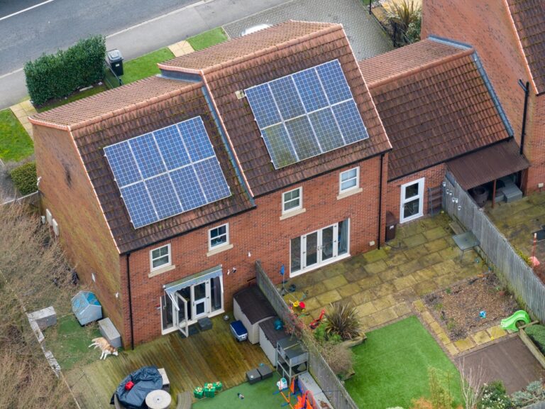 Aerial view of a house featuring solar panels on the roof.