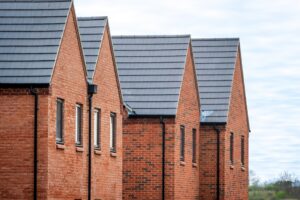 A series of red brick homes topped with black roofs in a row.