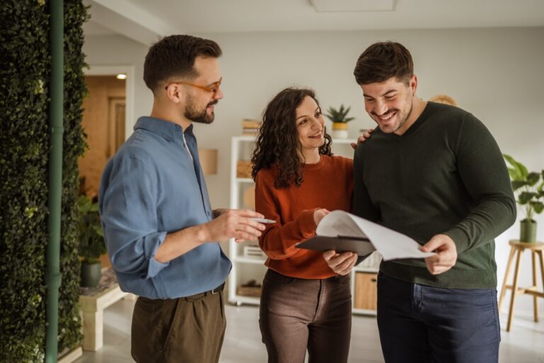 Estate agent presenting a document to two clients in an office setting.