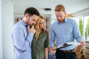 Three individuals reviewing a document together inside a home.