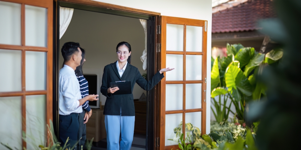Asian couple discussing property with a real estate agent.